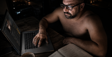 Hombre con gafas trabajando de noche frente a un portátil con las manos manchadas de grasa de taller, analizando cuánto se tarda en ganar dinero online en su libreta de estrategia.