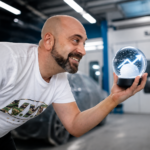 Noé Serrano en el taller de pintura de coches sosteniendo una bola de nieve con una flecha de crecimiento, representando el efecto bola de nieve en la Ruta 2032