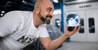 Noé Serrano en el taller de pintura de coches sosteniendo una bola de nieve con una flecha de crecimiento, representando el efecto bola de nieve en la Ruta 2032