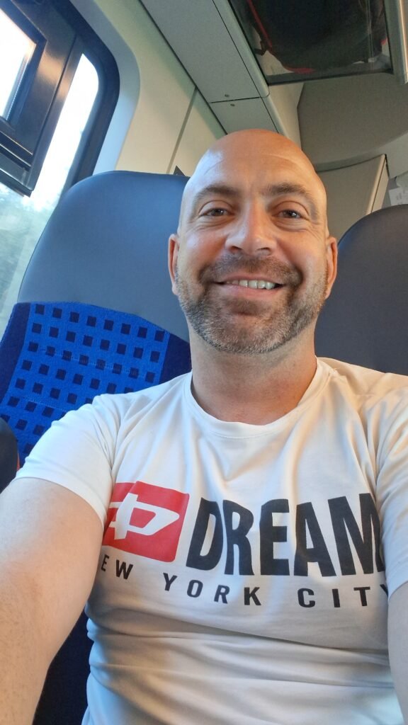 Noé Serrano sonriendo en un tren camino a Hemau, Alemania, reflejando el día a día real de empezar de cero en otro país.